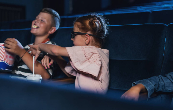 Small children with 3d glasses and popcorn in the cinema, watching film. - Fotografie, Obrázek