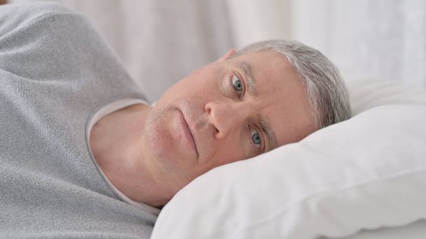 close-up van oude man wakker in bed denken - Foto, afbeelding