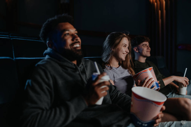 Cheerful young couple with popcorn in the cinema, talking. - Foto, imagen
