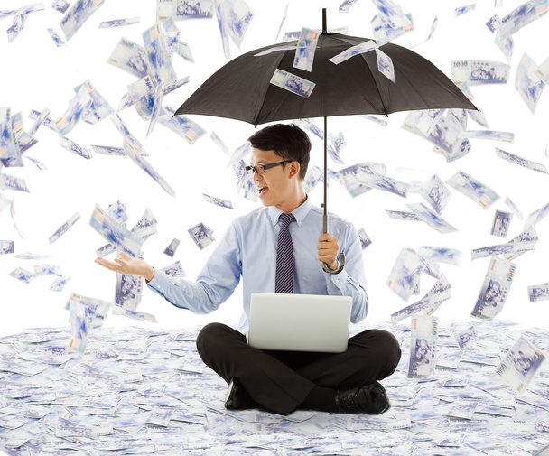 ο άνθρωπος των επιχειρήσεων κρατώντας μια ομπρέλα και την αλίευση χρήματα - Φωτογραφία, εικόνα