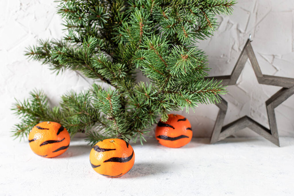 Mandarinen mit bemalten Streifen auf weißem Hintergrund mit einem Weihnachtsbaum. Das Konzept für das neue Jahr des Tigers für Kinder. Tigermandarinen für Kinderspaß - Foto, Bild