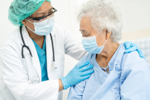 医師のヘルプアジアの高齢女性高齢者や高齢者の女性患者は、安全感染を保護し、 Covid-19コロナウイルスを殺すために病院で顔マスクを着用. - 写真・画像