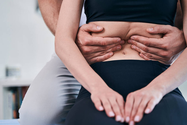 Male physiotherapist hands doing manual massage on female abdomen in medical office - Fotoğraf, Görsel