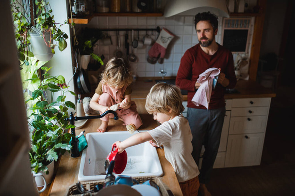 Mature father with two small children washing dishes indoors at home, daily chores concept. - Foto, Bild