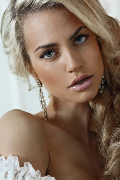 Gortret of a woman. Face close-up. Beautiful blonde, bride. Earrings in the ears. Look straight ahead. - Фото, зображення