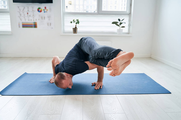 Акуратний сильний інструктор з фітнесу, що демонструє різні позиції йоги та фізичні вправи в студії
 - Фото, зображення