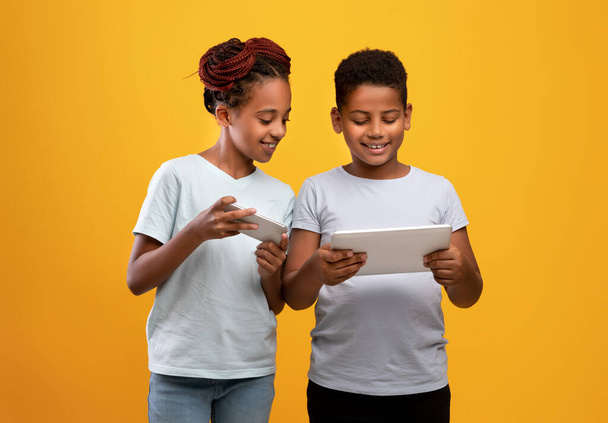 Zwart meisje met smartphone en jongen met digitale tablet - Foto, afbeelding