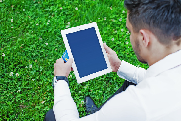 Молодой бизнесмен сидит в городском парке с планшетом
 - Фото, изображение