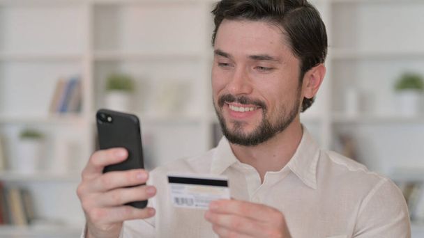 Młody człowiek dokonywania płatności online na smartfonie - Zdjęcie, obraz