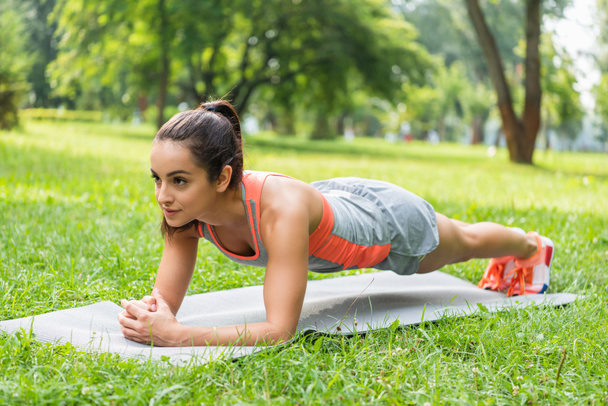 young fit woman with clenched hands doing plank on fitness mat  - 写真・画像