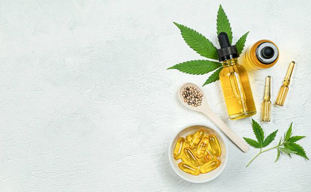 cbd olio, capsule, fiale, semi e foglie di cannabis fresca su sfondo grigio cemento vista dall'alto - Foto, immagini