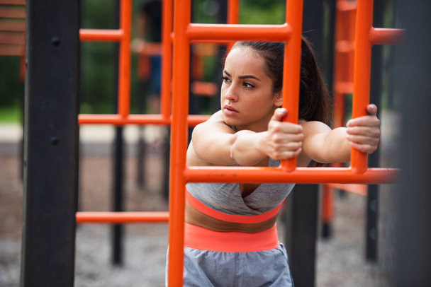 外のオレンジ色の垂直なはしごの近くで運動するスポーツウェアの女性 - 写真・画像