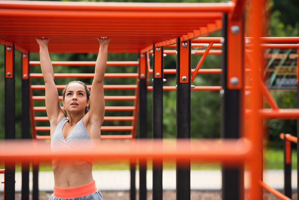 athletic woman exercising on blurred horizontal ladder outside - Foto, imagen