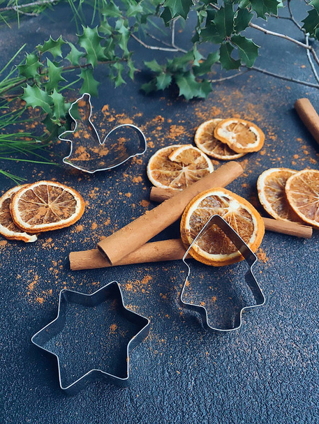 Fahéj rúd szárított szeletelt naranccsal, süti formák a sötét háttérben - Fotó, kép