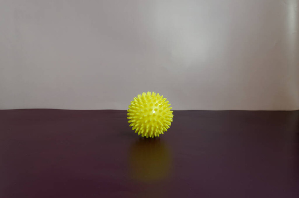 Bola de massagem amarela com agulhas em um fundo roxo - Foto, Imagem