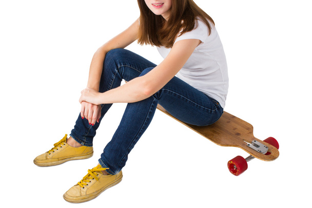 Young woman sitting on a skateboard - Zdjęcie, obraz