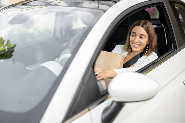 Woman drives a car with parcels in her hands - Fotó, kép