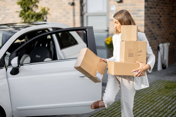 Жінка з посилками біля її машини і будинку
 - Фото, зображення