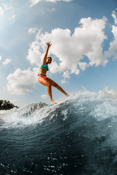 young wet woman in colorful swimsuit masterfully balancing on wave on wakesurf board. - Fotoğraf, Görsel