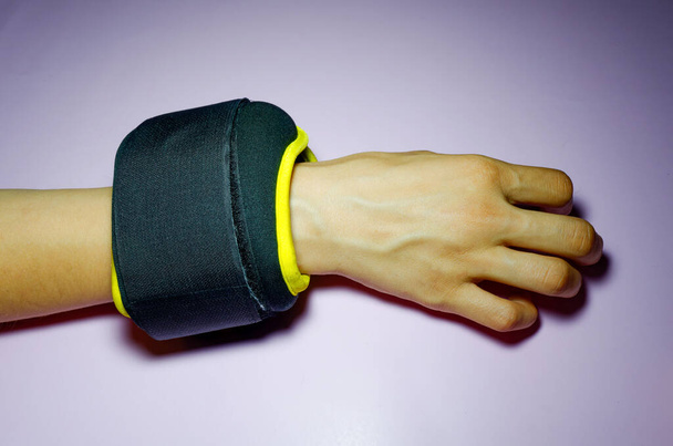 black with yellow fabric wrist ankle weights on pink background - Foto, Imagen