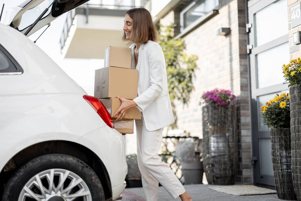 Жінка з посилками біля її машини і будинку
 - Фото, зображення