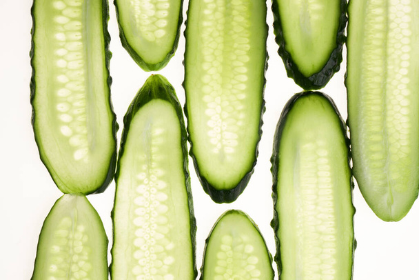 Cucumber green slices pattern isolated on white background. Creative cucumbers wallpaper, food backdrop design - Valokuva, kuva