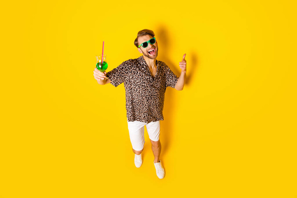 Full length φωτογραφία του γοητευτικό αστείο νεαρός φορούν λεοπάρδαλη ρούχα που δείχνουν σας αλκοόλ απομονωμένο κίτρινο χρώμα φόντο - Φωτογραφία, εικόνα
