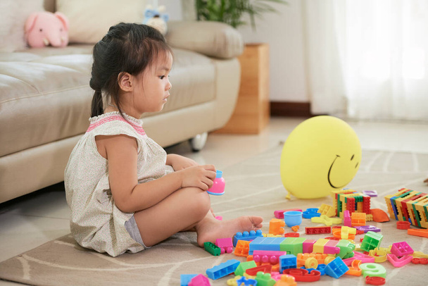 Pensativo chica jugando con juguetes en casa - Foto, imagen