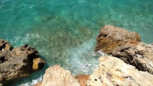 Waves splash against rocks. Marine theme with copy space. Top view natural background of rippled sea-green sea water. Aerial view of aquamarine sea surface. Rough sea and stone texture. - Footage, Video