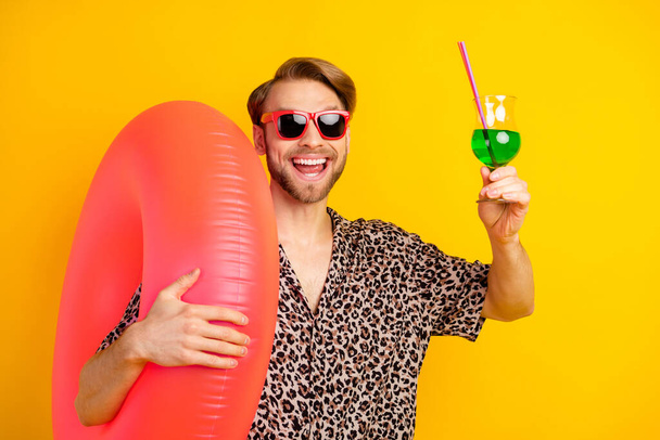 Photo of excited charming guy wear leopard eyewear enjoying alcohol holding inflatable buoy isolated yellow color background - 写真・画像