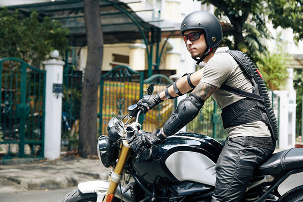 Hombre en equipo de protección sentado en la motocicleta - Foto, Imagen