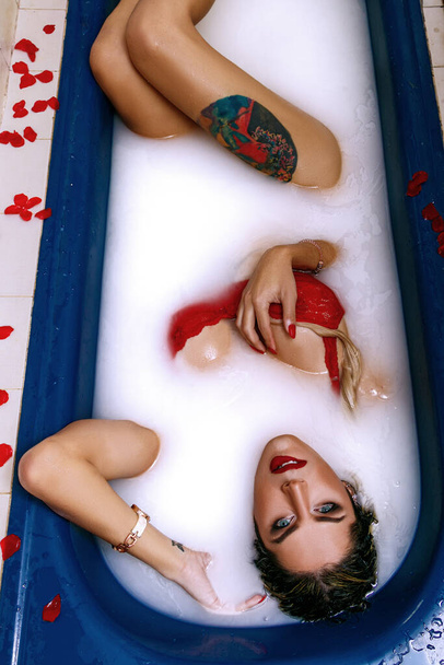 rubia transexual en lencería roja, en el sofá en el apartamento y en el baño de leche - Foto, Imagen