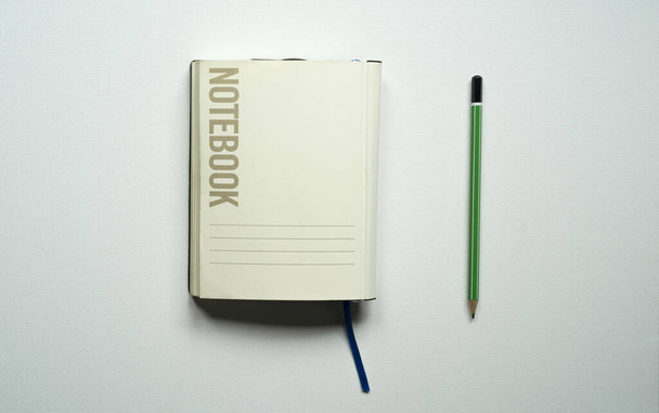 notebook s prostorem pro text, stůl, modrá záložka, zelená tužka, na bílém pozadí, fotografie shora - Fotografie, Obrázek