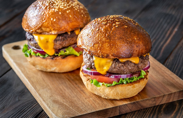 Two burgers on the wooden board close up - Φωτογραφία, εικόνα