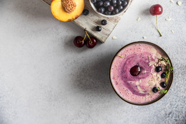 Smoothie bowl with blueberry, almond slices with fresh berries and fruit on wooden cutting board. Top view. Selective focus. Copy space. - Fotó, kép