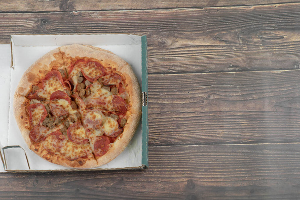 Mixed tasty pizza with salami and meat on carton box. High quality photo - Photo, Image