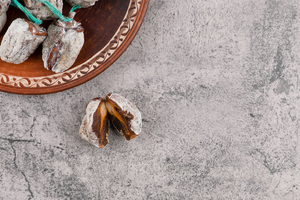 Um prato redondo cheio de frutos de cáqui secos colocados em uma mesa de pedra. Foto de alta qualidade - Foto, Imagem