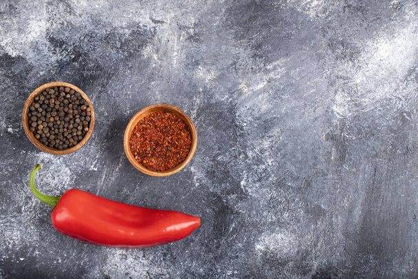 Červený chilli pepř s mletými pepřovými vločkami a pepřovými kukuřicemi na mramoru. Kvalitní fotografie - Fotografie, Obrázek