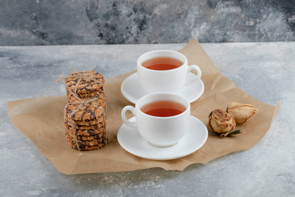 Sabrosas galletas con semillas y chocolate con taza de té sobre fondo de mármol. Foto de alta calidad - Foto, imagen