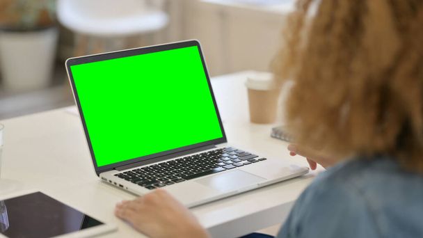 Achteraanzicht van Afrikaanse vrouw met behulp van laptop met groene Chroma Key Screen  - Foto, afbeelding