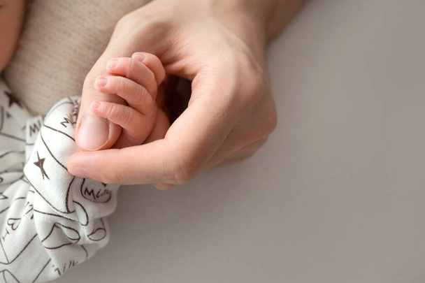 gelukkig mam liefdevol houden de vingers van een pasgeboren baby - Foto, afbeelding