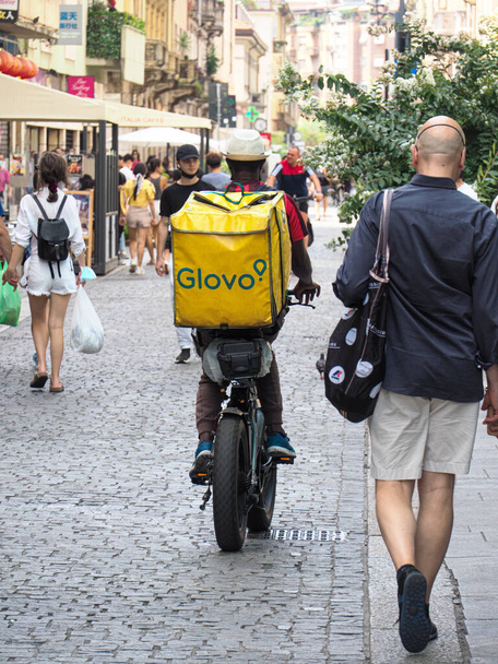 MILAN, ITALY - Aug 08, 2021: A rear view of a rider delivering food ordered using a delivery companies app in Milan, Italy - Фото, изображение