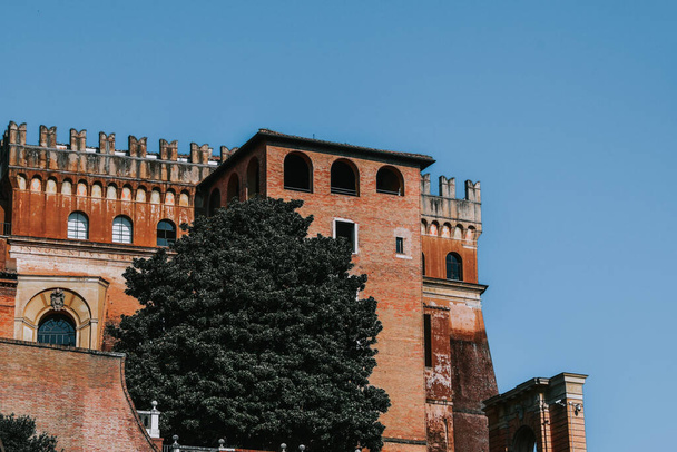 A vertical shot of a brown old stony building with tree against blue sunny sky in Rome, Italy - Фото, зображення