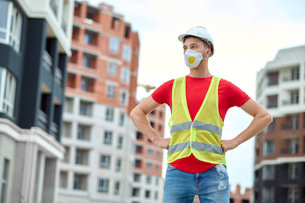 Male builder with hands on his hips looking away - Фото, зображення