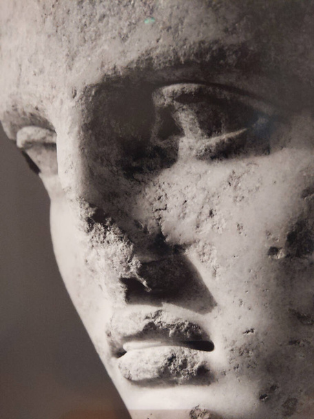 a closeup shot of aged damaged statue face with broken nose and lips - Foto, imagen