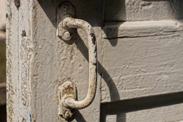 un viejo pomo de puerta de hierro gris sucio en tablones de puerta de madera blanca - Foto, Imagen