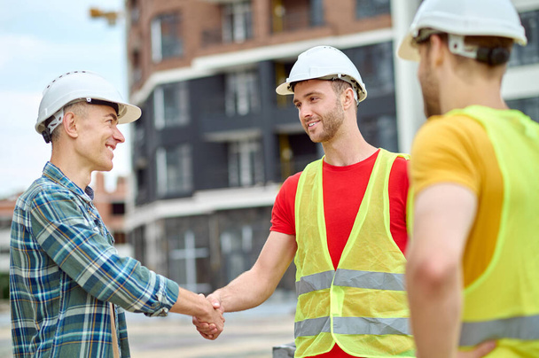 Handsome bearded Caucasian construction worker shaking his colleague hand - Photo, Image