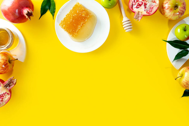 Honey, apple and pomegranate on a yellow background. Concept Jewish New Year Happy holiday Rosh Hashanah. Creative layout of traditional symbols. View from above. Flat lay. Copy space. Shana Tova - Fotoğraf, Görsel