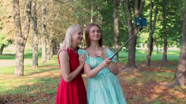 Happy mother and adult daughter take selfie in the park outdoors. Mother and adult daughter take selfie in the park outdoors. Mom kisses daughter on the cheek - Footage, Video