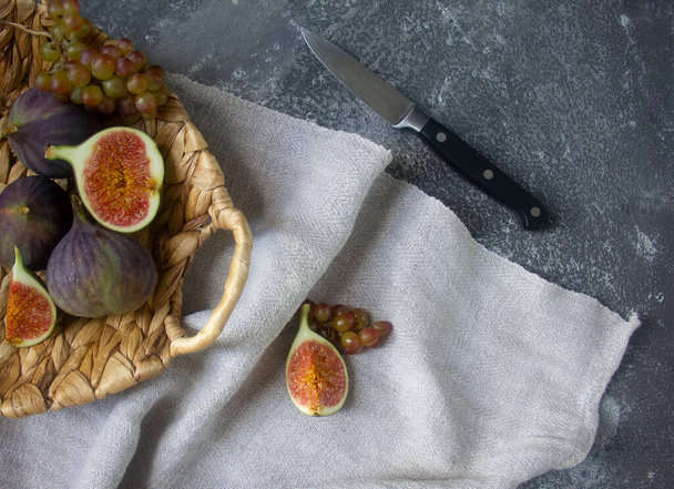  Fresh figs in a wicker basket on linen napkin on concrete background - Foto, afbeelding